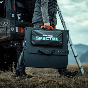 Dark Energy Spectre 200W portable solar panel carried outdoors near an off-road vehicle