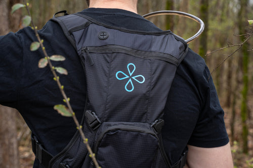 Puribag Adventure Pack, black ripstop hydration backpack with blue Puribag logo, worn in forest with filter kit visible