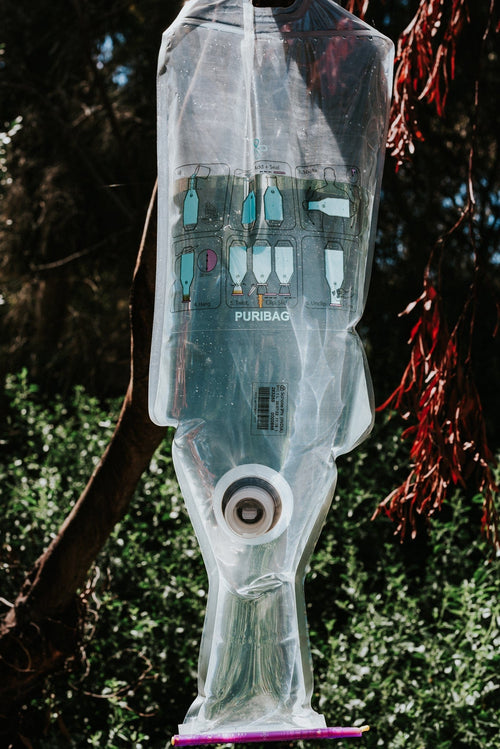 Puribag water purification bag hanging from tree outdoors, showing steps to purify water