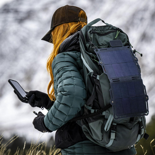 Dark Energy Spectre 8W portable solar charger attached to a backpack, charging a phone on a winter hike