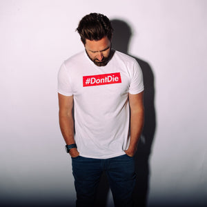The Hashtag men's white #DontDie t-shirt, a survival apparel graphic tee worn by a man looking down