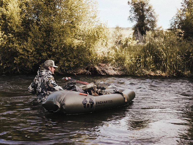 Man walks beside an inflated rapid raft in a stream