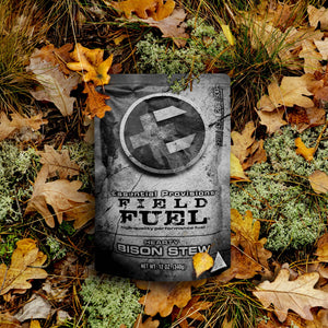 Essential Provisions FIELD FUEL Bison Stew performance meal pouch on a forest floor with autumn leaves and moss