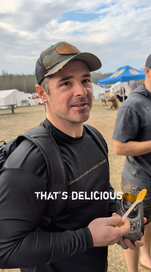Essential Provisions Bison Chili Meal, a smiling man enjoys this ready-to-eat survival food from a pouch outdoors