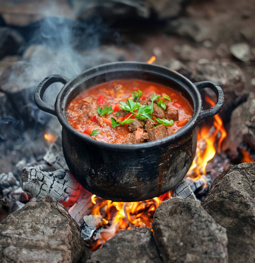 Essential Provisions Bison Stew, a ready-to-eat meal, heated in a pot over a roaring campfire