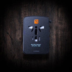 Int'l Wall Adapter by Dark Energy. Black universal travel power adapter with multiple outlets, 35W, on dark wood