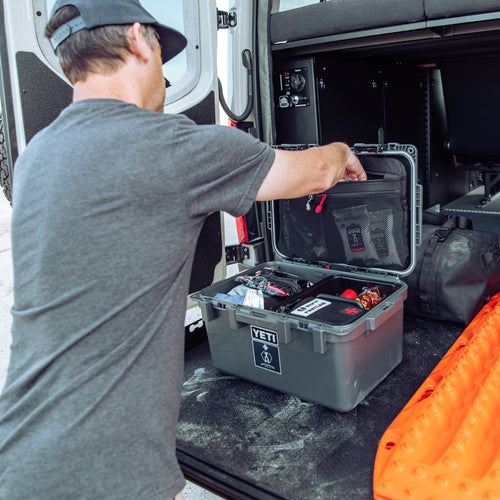 person opening the basecamp 30L survival system in the back of a sprinter van