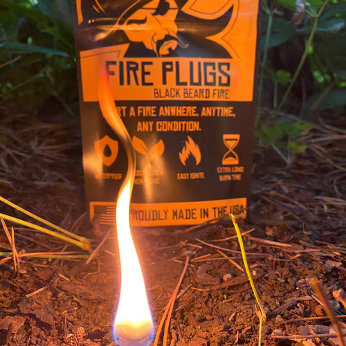 Black Beard Fire Plugs, a lit emergency fire starter burning on dirt with packaging displaying brand logo