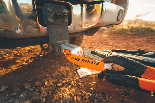 MAXTRAX Core Soft Shackle, orange and silver, attached to a truck's tow hitch receiver and recovery rope off-road