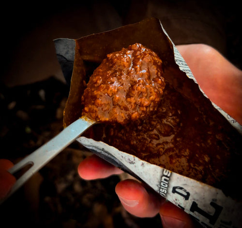 Essential Provisions BISON CHILI MRE, a ready-to-eat survival meal being eaten from its pouch with a spork
