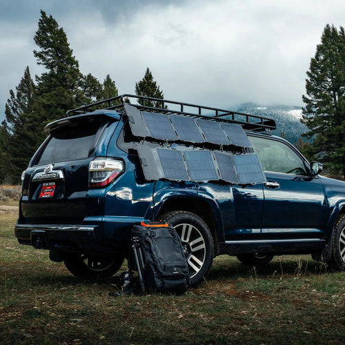 Spectre 56W portable solar panels by Dark Energy on a blue SUV, charging off-grid in a mountain setting