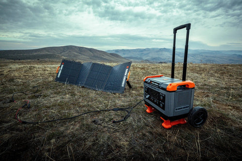 Recon 2000 portable power station with extendable handle and wheels, charging via Dark Energy solar panels outdoors