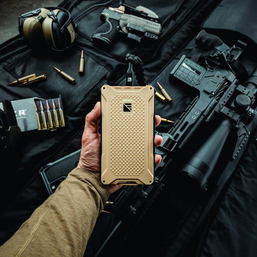 Poseidon Pro rugged power bank by Dark Energy with tactical firearms and ammo on a gear bag