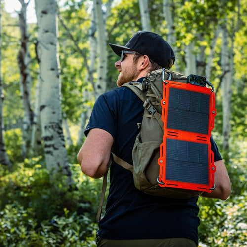 Dark Energy Spectre 8W orange solar panel attached to an olive backpack on a man hiking in a forest