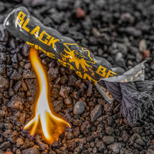 Grab & Go Fire Starter Kit by Black Beard, black rope fire starter with bright flame on dark rocks