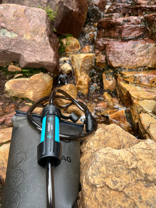 Puribag 2 Liter Hydration Bladder with Filter on wet rocks by a flowing stream for safe outdoor drinking water