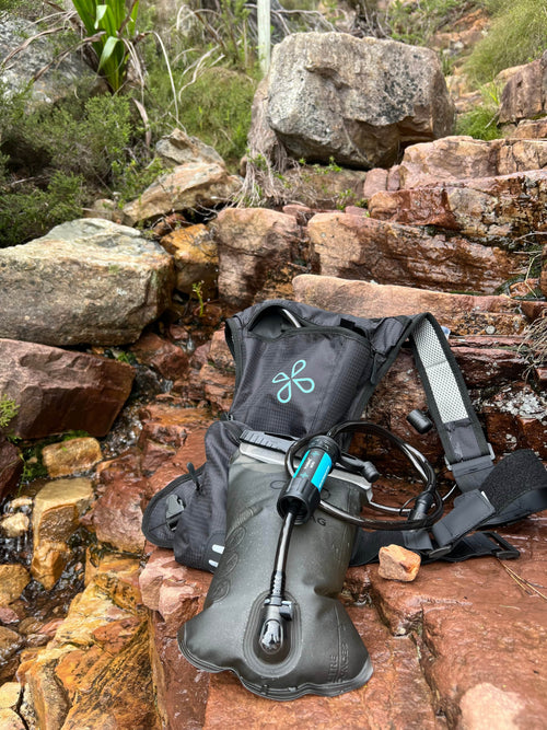 Puribag Adventure Bladder 2-liter hydration system with blue micro water filter on wet rocks by a stream