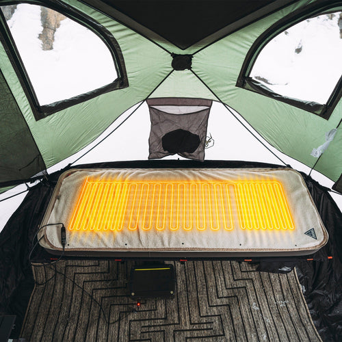 Ignik Outdoors Flipside Heated Bed Cover Fleece glowing warm inside a tent, powered by a battery pack