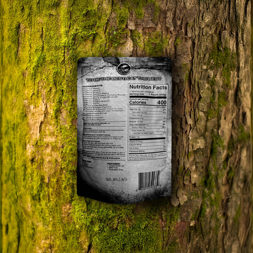 Essential Provisions Lentil Chili ready-to-eat meal pouch with nutrition facts against a mossy tree, survival food