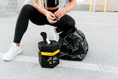 Klean Freak Body Wipes - The Jug: black hexagonal container with a wipe, next to a person in workout gear and gym bag
