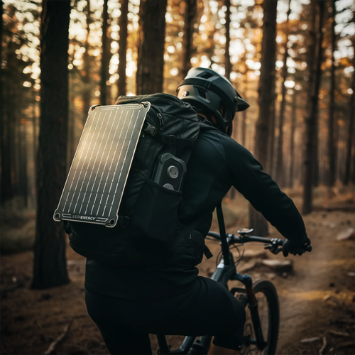 Lion Eclipse Mag portable solar panel by LIONENERGY on a backpack, used by a mountain biker for off-grid power in a forest