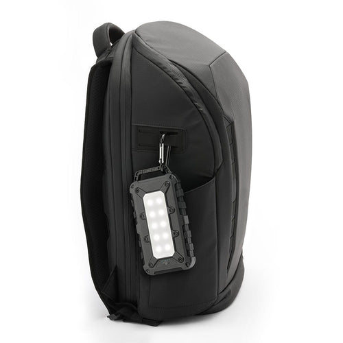 Lion Cub rugged LED emergency light and power bank clipped to a dark backpack