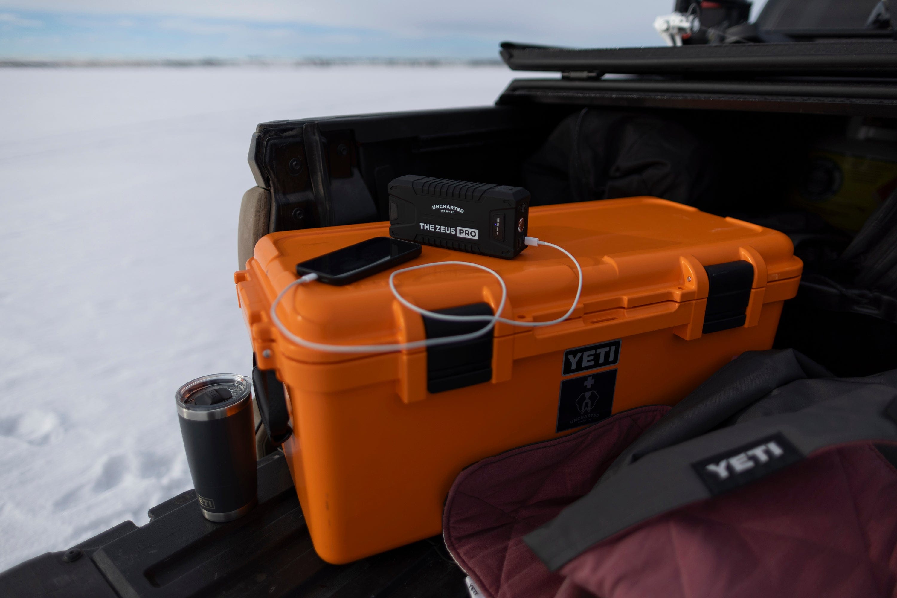 Uncharted Zeus Pro portable power bank charging phone on Basecamp 60L survival kit