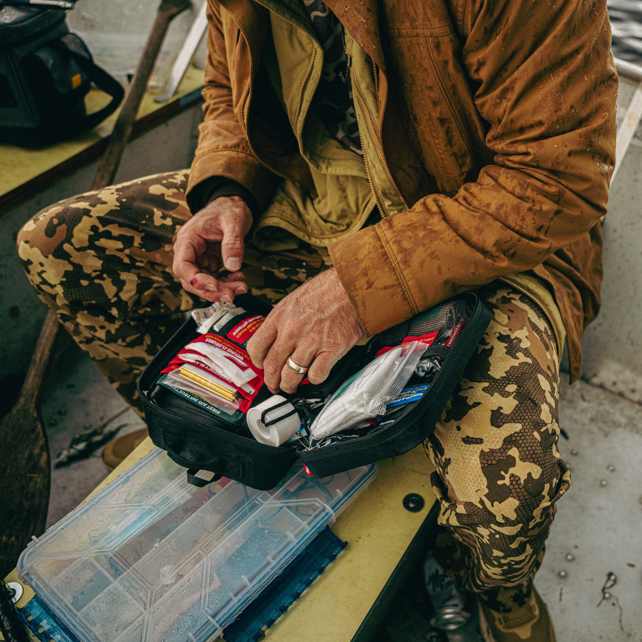 First aid plus being used by a man with a cut finger, showing bandages and tape, in an outdoor boat setting