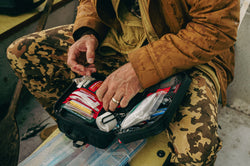 First aid plus being used by a man with a cut finger, showing bandages and tape, in an outdoor boat setting