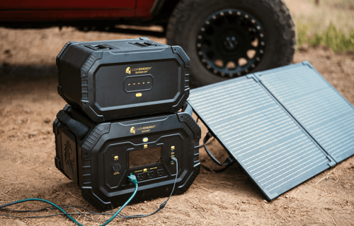 Lion Safari portable power stations stacked with solar panel, charging outdoors by a vehicle