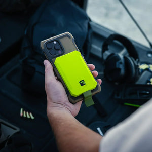 Dark Energy Poseidon Nano lime green portable charger with strap, attached to an iPhone in a rugged case, held in a vehicle
