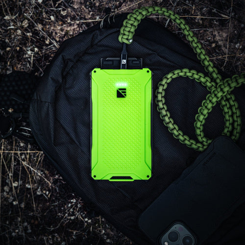 Dark Energy Poseidon Pro, bright green rugged power bank with glowing lights, connected to a paracord lanyard on a black backpack