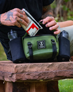 Man puts triage kit into Uncharted Supply Co. Park Pack with water bottles