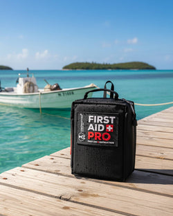 Waterproof First Aid Pro kit on a sunny dock next to a boat in vibrant turquoise water with distant islands