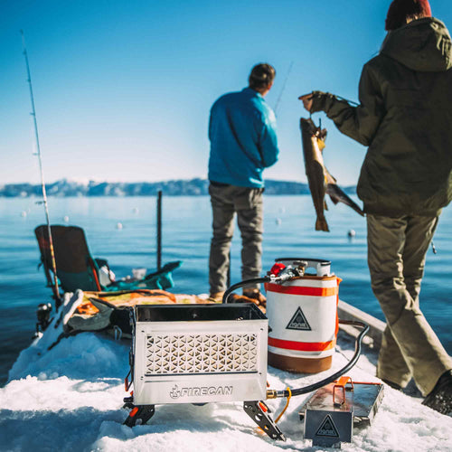 FireCan Deluxe Fire Pit by Ignik, a portable propane fire pit, used for ice fishing on a snowy lake