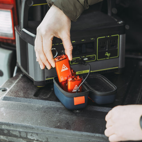 Ignik Ripple Rechargeable Hand Warmers being placed into a pouch, plugged into a portable power station in a truck