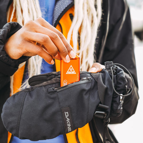 Ripple Rechargeable Hand Warmers: Person placing an orange Ignik hand warmer into a black Dakine glove for winter warmth