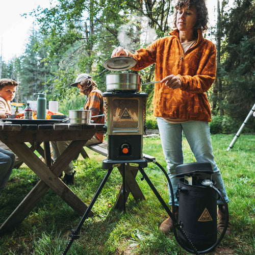 Skullet Deluxe Heater Stove Cook Set by Ignik Outdoors, woman cooking on camping stove with propane tank