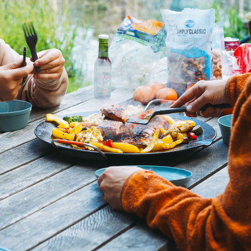 Ignik Outdoors Skullet Deluxe Heater Stove Cook Set on a rustic table, cooking steak and veggies outdoors