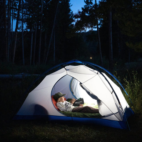 Person inside a tent in a forest at night using the zeus air as a flashlight