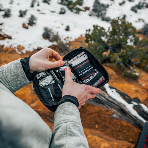 Person holding a first aid core with contents in a snowy landscape