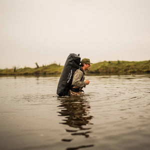 Duck hunter wading through the water with a 100L vault on his back