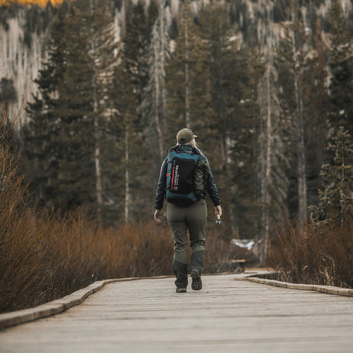 Woman walking on a wooden walkway with a seventy2.0 Pro shell on her back