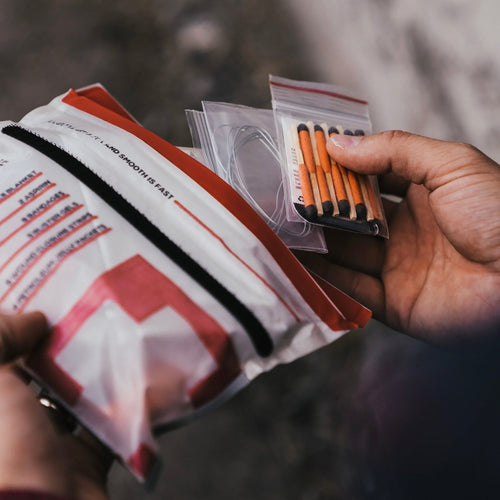 Person holding a triage kit with medical supplies and matches
