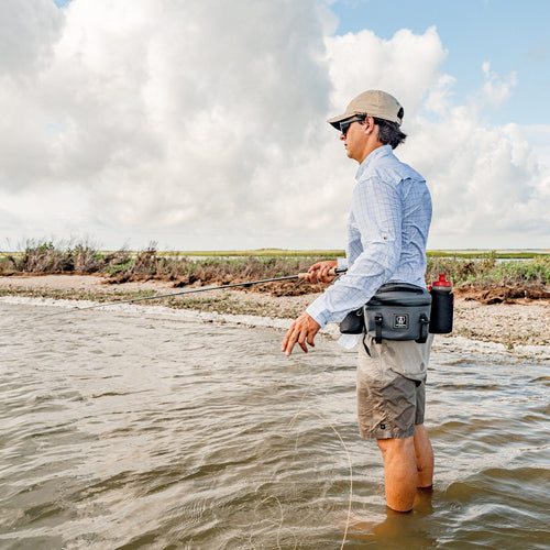 Man fishing in shallow water with a park pack and rod