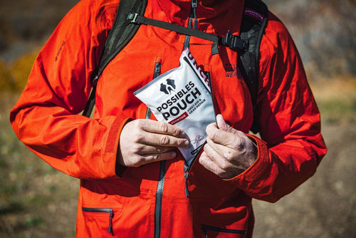 Person in a red jacket holding a possibles pouch