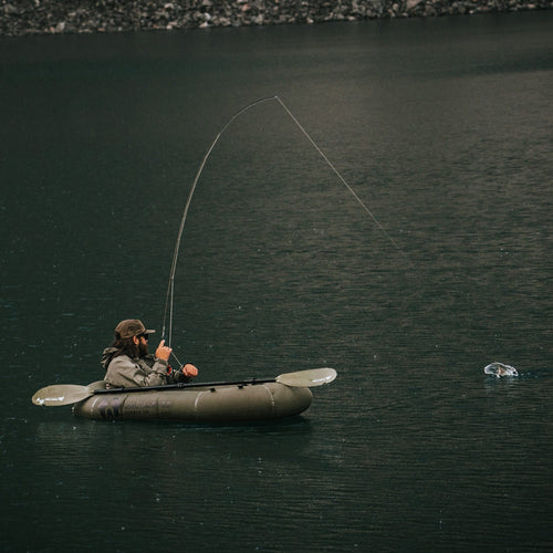 Person fishing from a kayak on a calm lake inside the rapid raft
