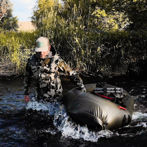 man carrying rapid raft up a stream