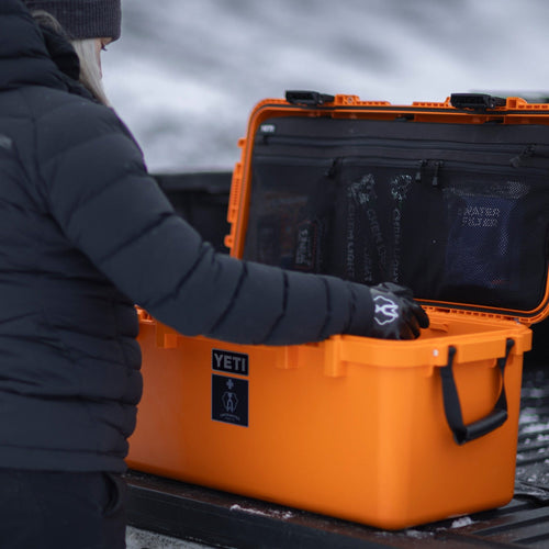 Person opening an orange basecamp 60L outdoors