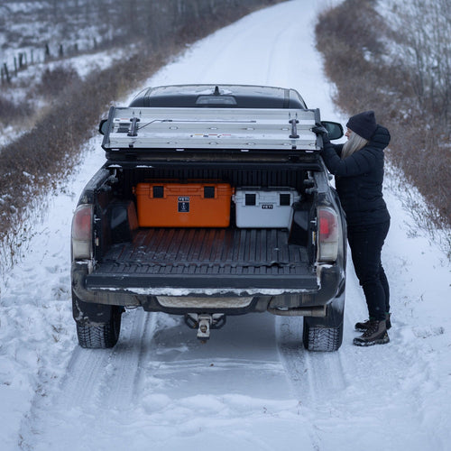 Person loading items into the back of a truck on a snowy road